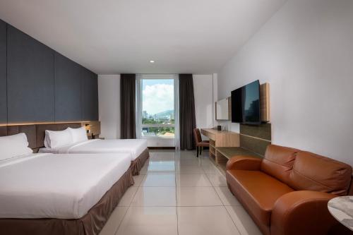 a hotel room with two beds and a couch at One Pacific Hotel and Serviced Apartments in George Town