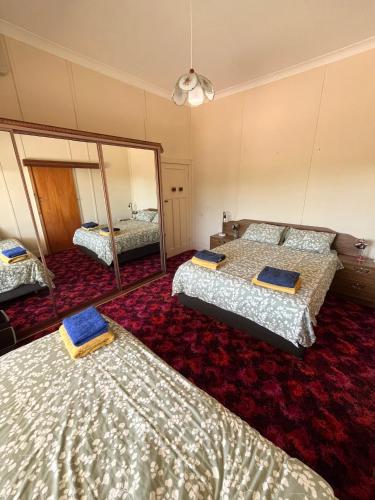a room with three beds and a mirror at Stay @ Ray's in West Wyalong