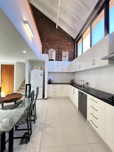 a kitchen with white cabinets and a table and chairs at 17 Rare Cool Urban-Style Nedlands 4BR-Parkng&Pool in Perth