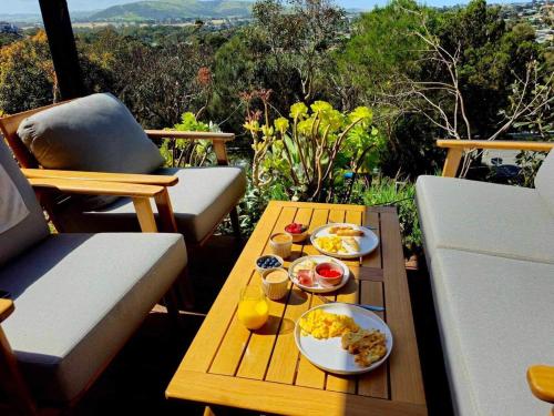 a table with plates of food and drinks on a balcony at Wren House Victor Harbor in Victor Harbor