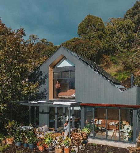 a house with glass doors and a person standing in the window at Wren House Victor Harbor in Victor Harbor