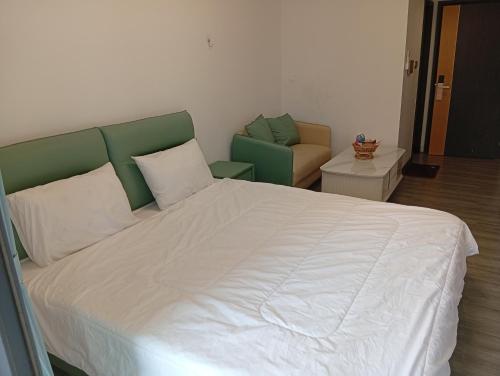 ein Schlafzimmer mit einem großen weißen Bett und einem Stuhl in der Unterkunft Hollyday Condo in Sihanoukville