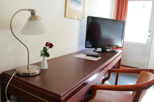 a desk with a computer monitor and a lamp on it at Hotel Medio Fredericia in Fredericia