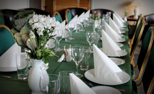 a long green table with white plates and flowers on it at Hotel Medio Fredericia in Fredericia