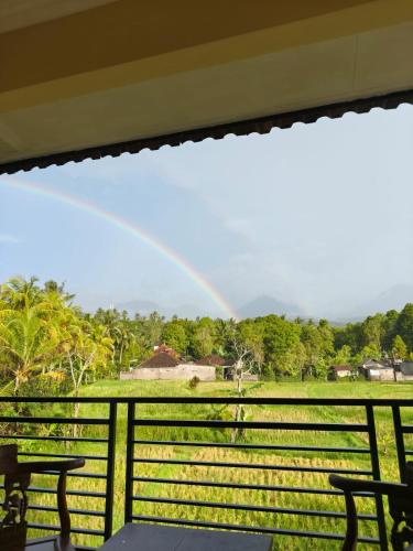 a rainbow over a field with a fence and chairs at Yoga Homestay in Munduk