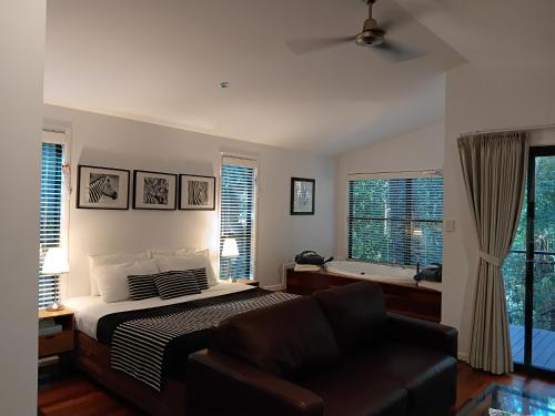 a bedroom with a bed and a chair and a tub at Amore On Buderim Rainforest Cabins in Buderim