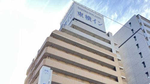 a tall building with a sign on top of it at Toyoko Inn Kobe Sannomiya-eki Higashi in Kobe
