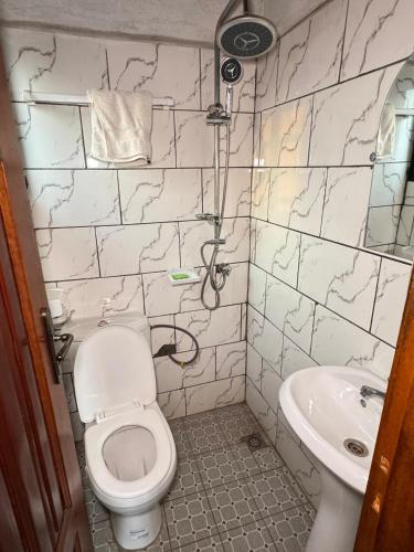 a bathroom with a toilet and a sink at Abu Dhabi CC Hotel in Limbe
