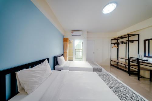 a bedroom with two white beds and a bathroom at Salin Home Hotel Ramkhamhaeng in Bangkok