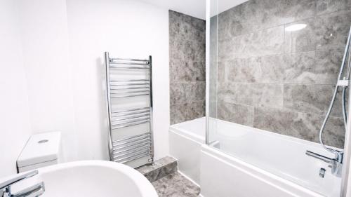 a bathroom with a toilet and a tub and a sink at AMETHYST - 4br all with ensuite & parking in Cambridge