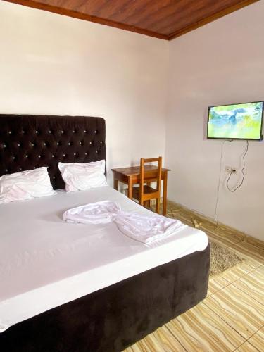 a bedroom with a bed and a tv on the wall at Abu Dhabi CC Hotel in Limbe