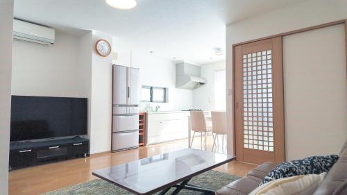 a living room with a glass table and a kitchen at 9Stay市原 in Ichihara