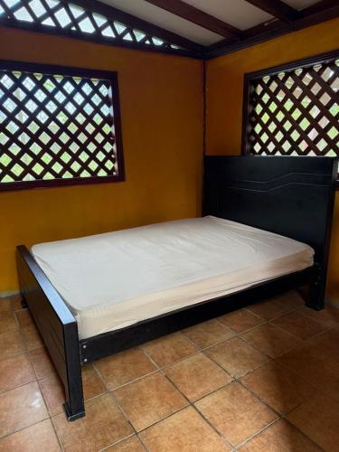 a bed in a room with two windows at Cabinas Cable Talamanca in Puerto Viejo