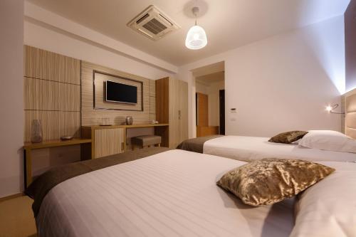 a hotel room with two beds and a television at Premium Wellness Institute in Bucharest