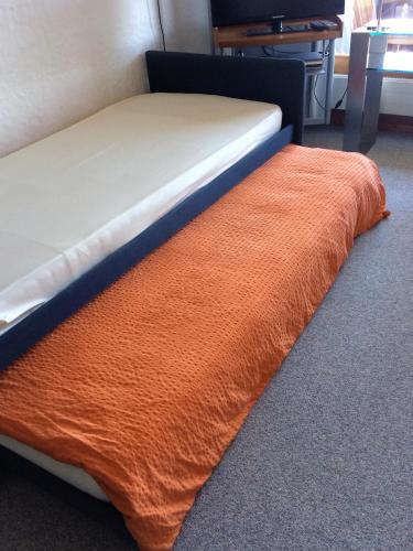 a bed with an orange blanket on the floor at Panorama in Villars-sur-Ollon