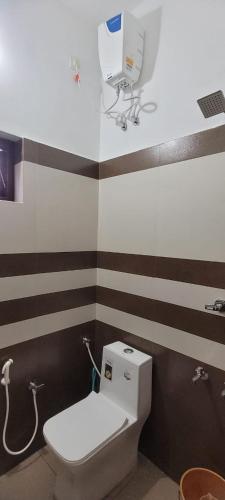 a bathroom with a white toilet and brown and white stripes at Krishna stays in Manattala
