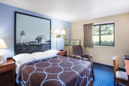 a hotel room with a bed and a chair and a window at Super 8 by Wyndham Massena NY in Massena