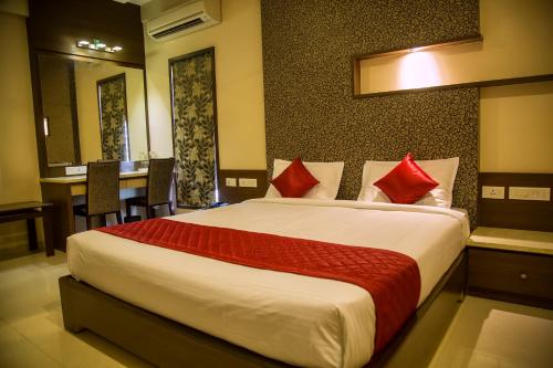 a bedroom with a large bed with red pillows at Hotel Sri Sakthi in Tiruppūr
