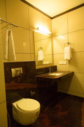 a bathroom with a toilet and a sink and a mirror at Hotel Sri Sakthi in Tiruppūr