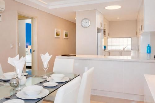 a kitchen with a glass table and white cabinets at The White Pearl Apartment Direct Ocean Views Top Floor in Perth