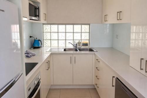 a white kitchen with a sink and a window at The White Pearl Apartment Direct Ocean Views Top Floor in Perth