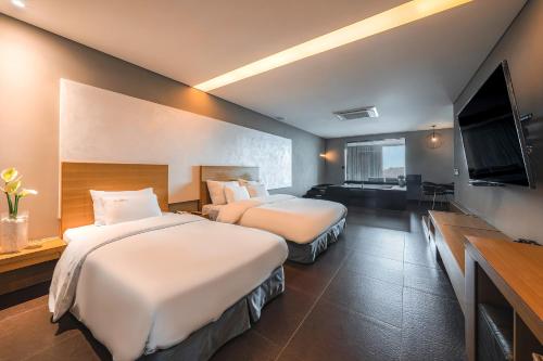 a hotel room with two beds and a flat screen tv at Hotel Hills in Paju