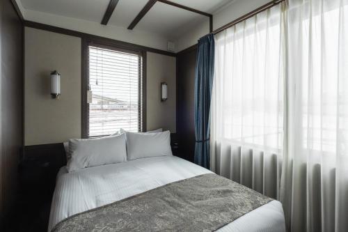a bedroom with a bed and a large window at JR Mobile Inn Hakodate in Hakodate