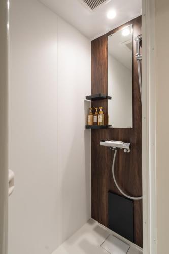 a bathroom with a shower with a mirror at JR Mobile Inn Hakodate in Hakodate