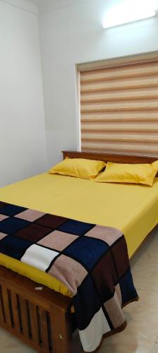 a bed in a room with a yellow and blue blanket at Ivory Suites Meadows in Kozhikode
