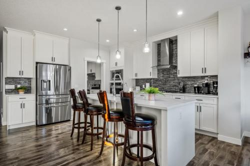 a kitchen with white cabinets and a island with bar stools at Luxury Retreat For Large Groups in Calgary