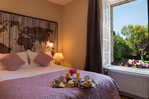 Una habitación de hotel con una cama con una bandeja de comida. en Manoir de la Roche Torin, The Originals Relais (Relais du Silence), en Courtils
