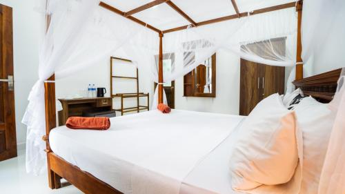 a bedroom with a white bed with a wooden canopy at Sunrise Cottage in Sigiriya