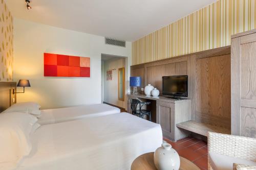 a hotel room with a bed and a tv at Villasanpaolo Resort & Spa in San Gimignano