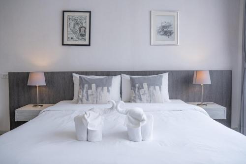 a bedroom with two white beds and two lamps at Ratchadamnoen Residence in Bangkok
