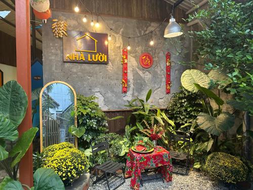 a garden with a table and a sign on a wall at Nhà Lười Homestay in Hue