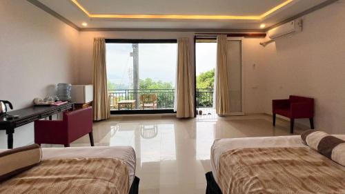 a bedroom with two beds and a desk and a balcony at Yoga bale house3 in Padangbai