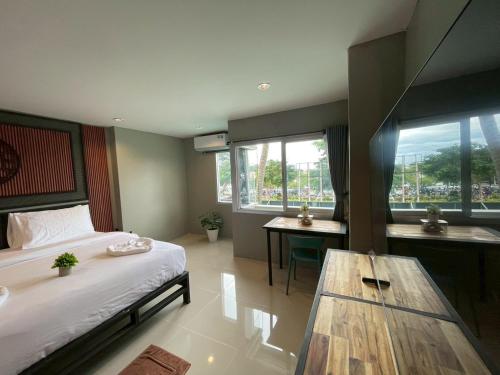 a bedroom with a bed and a table and windows at Amazing Inn Koh Phangan in Thong Sala