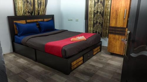 a bedroom with a bed with a red blanket and blue pillows at Bamboo Planet Resort in Vythiri