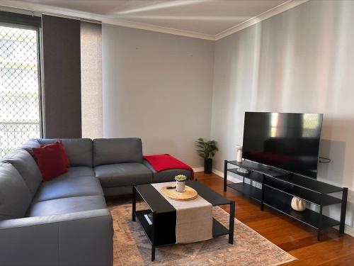 a living room with a couch and a flat screen tv at 73 Serene 2BR Apt Perth CBD Pool-Gym & FREE Parkng in Perth