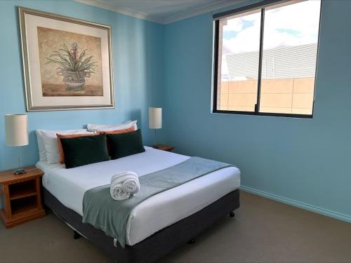 a bedroom with a large bed with blue walls and a window at 73 Serene 2BR Apt Perth CBD Pool-Gym & FREE Parkng in Perth