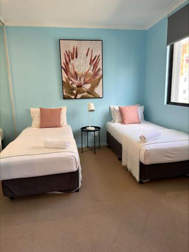 two beds in a room with blue walls at 73 Serene 2BR Apt Perth CBD Pool-Gym & FREE Parkng in Perth