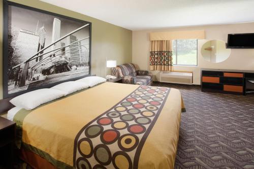 a hotel room with a large bed and a chair at Super 8 by Wyndham Dwight in Dwight
