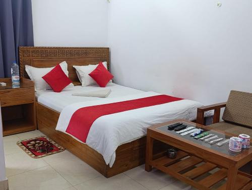 una camera da letto con un letto con cuscini rossi e un tavolo di Naioree Studio Apartment a Cox's Bazar
