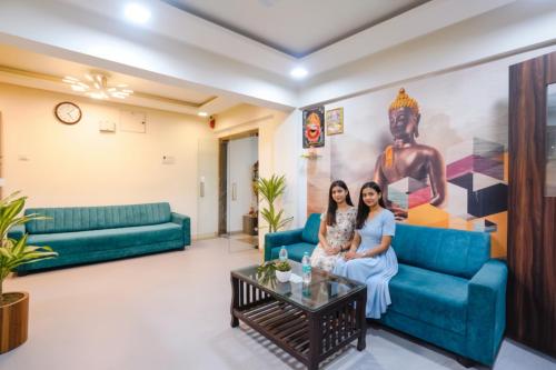 two women sitting on a couch in a living room at FabHotel Arsh Executive Inn in Mumbai