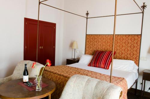 a hotel room with a bed, table, lamp, and bedspread at Palacio Rejadorada in Toro