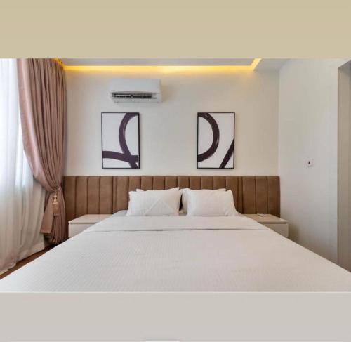 a bedroom with a large white bed with three pictures on the wall at Home helpers in Lagos