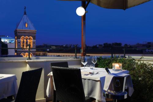 une table avec des verres à vin et une tour d'horloge en arrière-plan dans l'établissement Hotel Artemide, à Rome