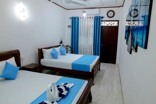 a bedroom with two beds with blue pillows at Arunella Beach Villa in Tangalle