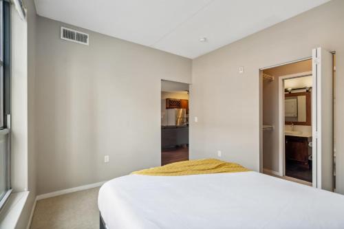 a bedroom with a white bed and a hallway at CozySuites 2BR Mill District with pool, gym #04 in Minneapolis
