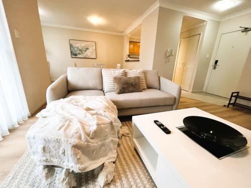 a living room with a couch and a table at 10 CBD Resort 2BR Secure Suite Pool Gym & Parking in Perth